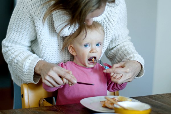 A mom is shown feeding her young daughter