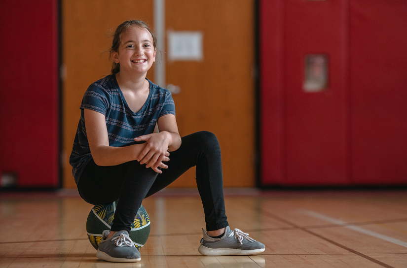 Girl Sitting On A Basketball